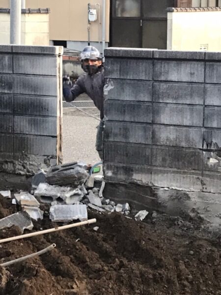ブロック塀を解体中、作業員がブロック塀から顔を出している