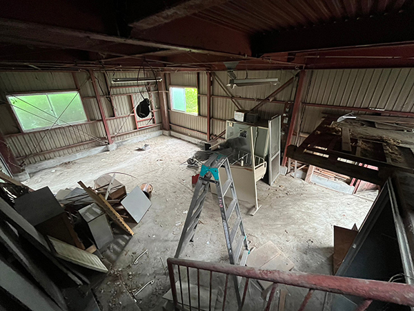 鉄骨造納屋の一階の内部。鉄製の箱や、農具機械が置かれています。